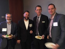 People in business attire holding dinner plates and smiling at camera