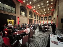 Open hall filled with people sitting at poker tables