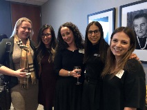 Five women wearing semi formal attire and smiling at camera