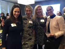 Four women wearing semi formal attire and smiling at camera
