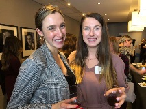 Two women holding wine glasses and smiling at camera