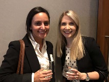 Two women holding drink glasses smiling at camera