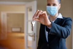 Real estate agent wearing a mask handing over keys