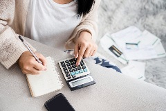 Mother calculating bills with calculator and notepad