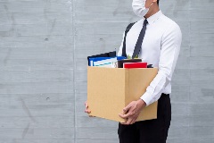 Person with packed desk supplies in box wearing mask